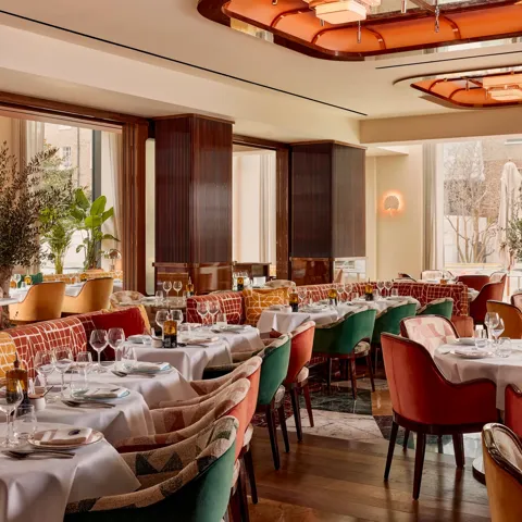 Elegant restaurant with plush velvet chairs, white tablecloths, and art deco ceiling lights.