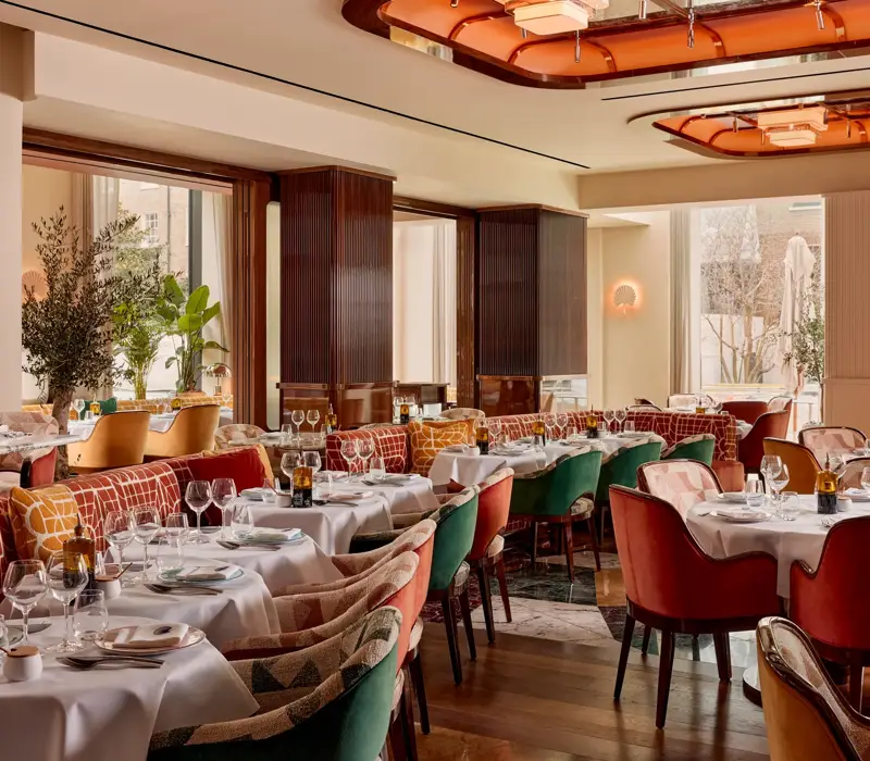 Elegant restaurant with plush velvet chairs, white tablecloths, and art deco ceiling lights.