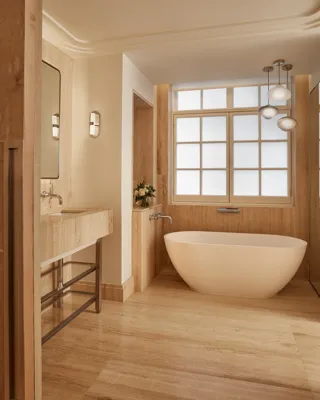 Minimal bathroom with freestanding bath, stone vanity and window, featuring warm wood tones, soft lighting and clean contemporary design