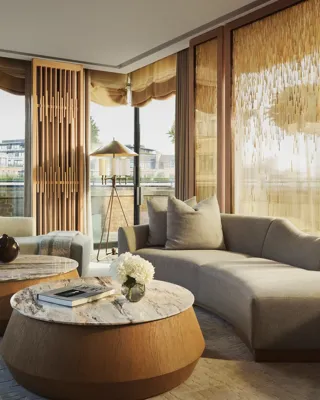 Penthouse living room with curved sofas, round marble tables, and floor-to-ceiling windows with golden drapes