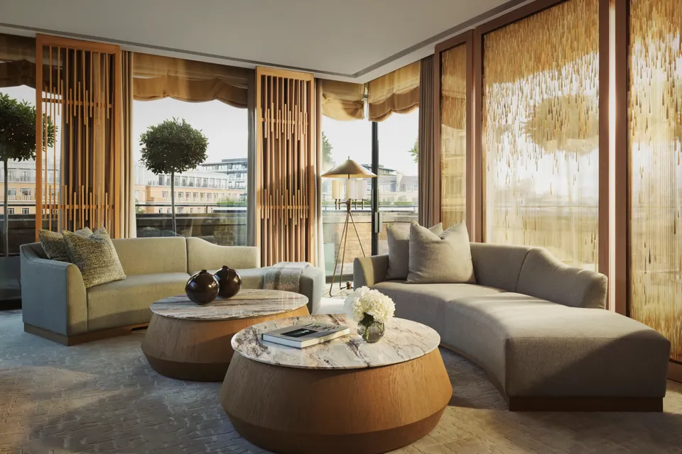 Penthouse living room with curved sofas, round marble tables, and floor-to-ceiling windows with golden drapes