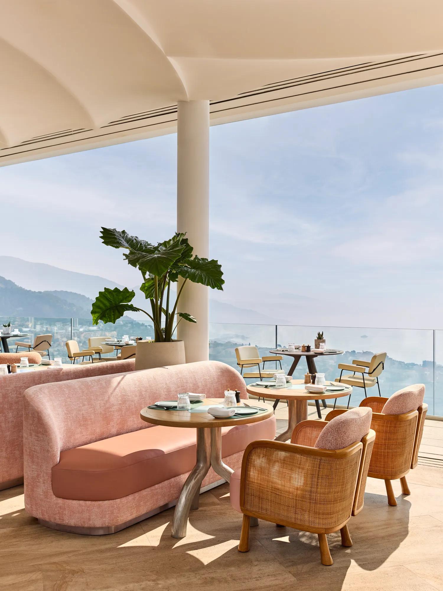Open-air terrace with pastel seating, potted plants, and sea views under a cream canopy at The Maybourne Riviera