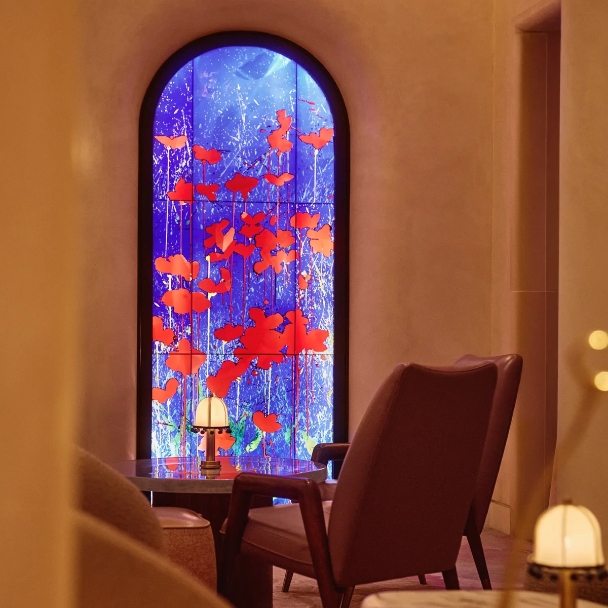 Lounge seating facing a tall arched window with vivid blue and red art glass.