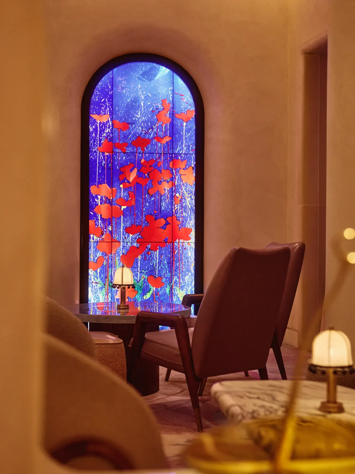 Lounge seating facing a tall arched window with vivid blue and red art glass.