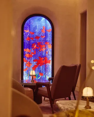 Lounge seating facing a tall arched window with vivid blue and red art glass.