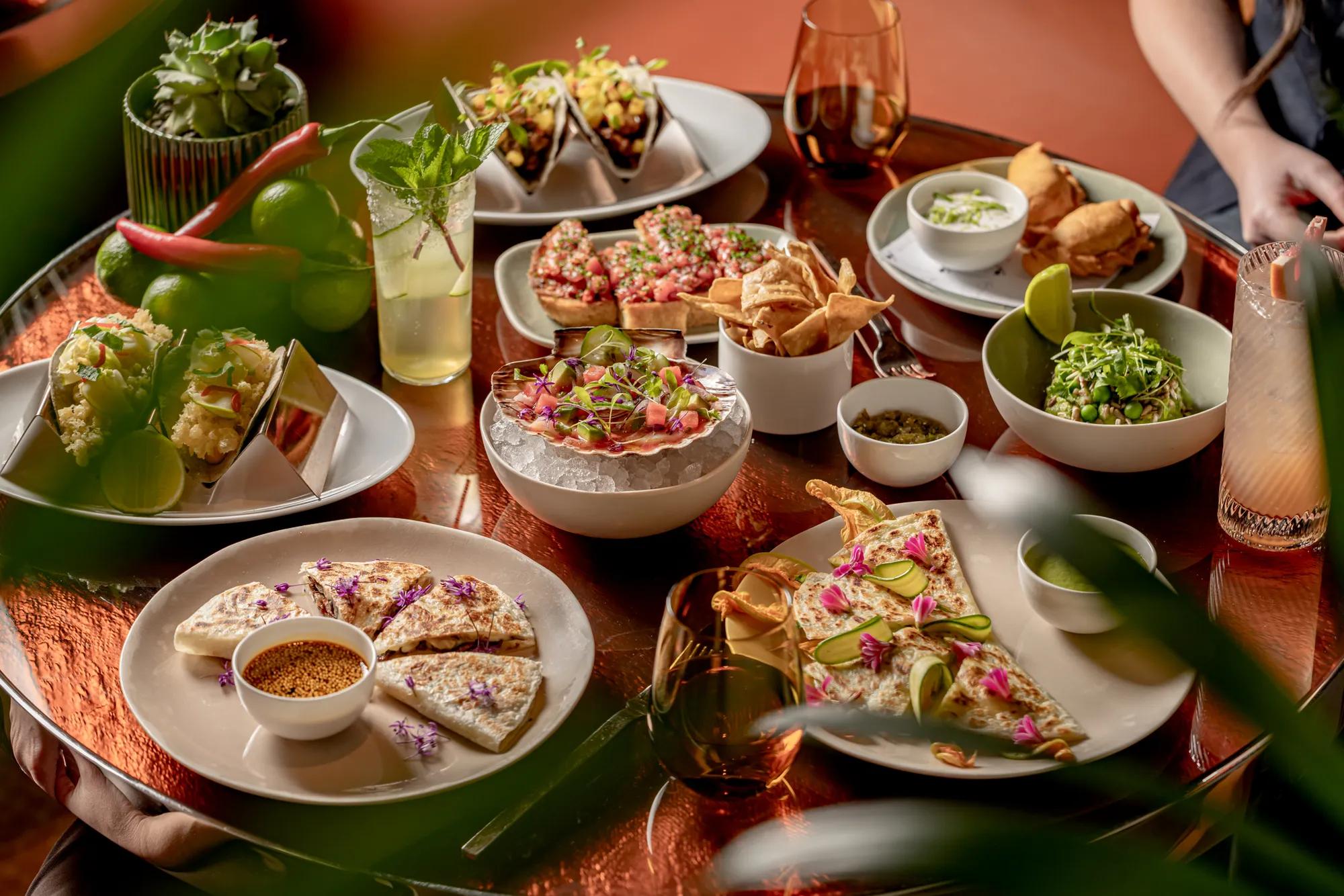 Table filled with tacos, quesadillas, ceviche, salads, cocktails and shared plates at abc kitchens restaurant.