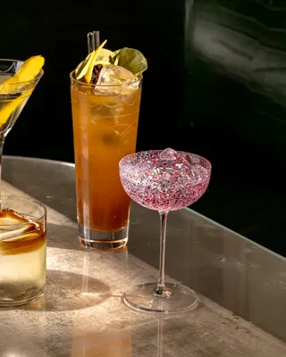 Assortment of five cocktails in various glassware, with ice, straws, and fresh fruit accents.