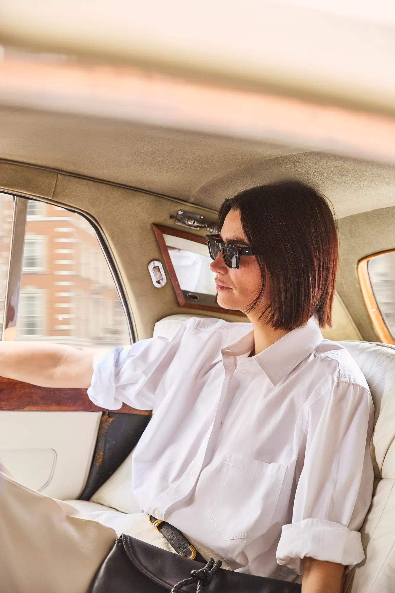 Guest seated in the back of a classic car, looking out of the window during a city journey.