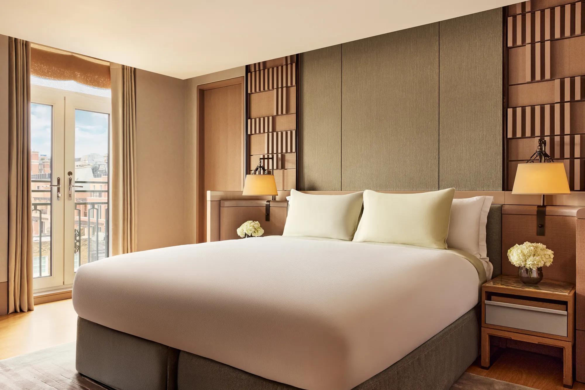 Bedroom in the Crescent Pavilion Penthouse with king bed, soft lighting, and French doors opening to a balcony.
