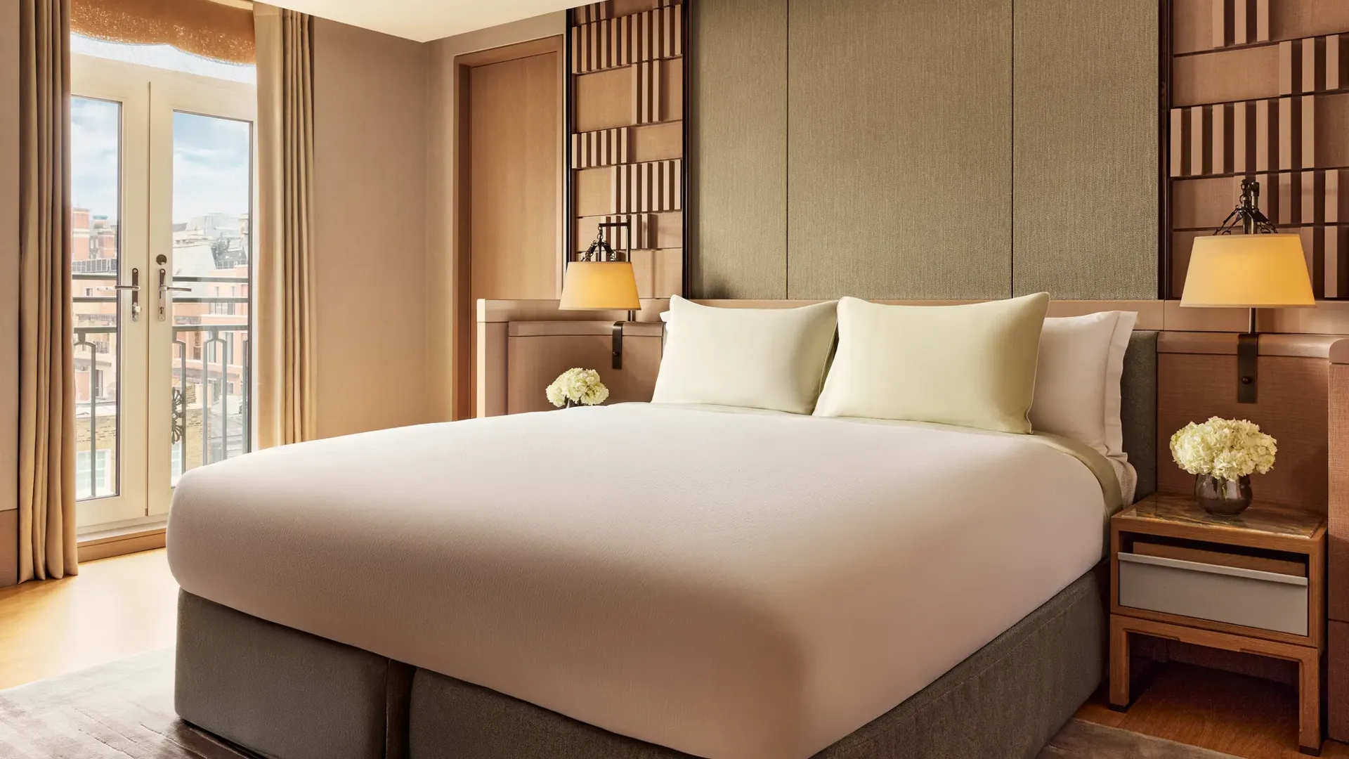 Bedroom in the Crescent Pavilion Penthouse with king bed, soft lighting, and French doors opening to a balcony.