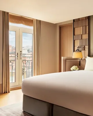 Bedroom in the Crescent Pavilion Penthouse with king bed, soft lighting, and French doors opening to a balcony.