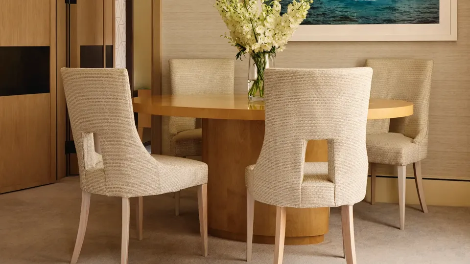 Intimate dining space with a circular wooden table and upholstered chairs, accented by a framed photograph of blue icebergs.