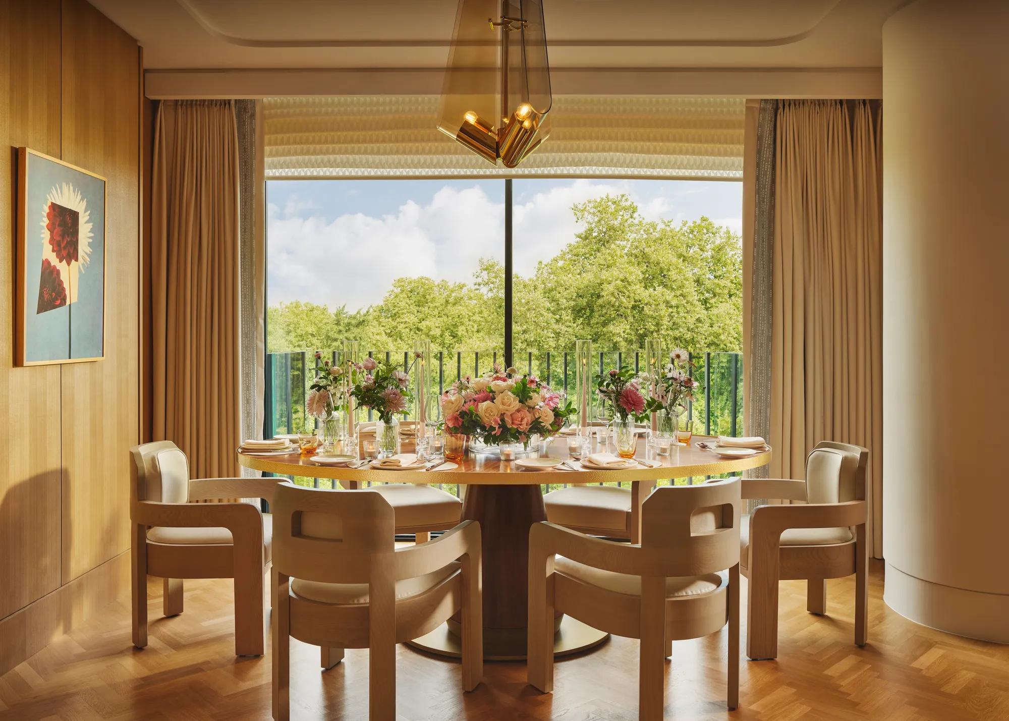 Private dining room with floral table setting, contemporary light wood chairs, large window, and views of Hyde Park.