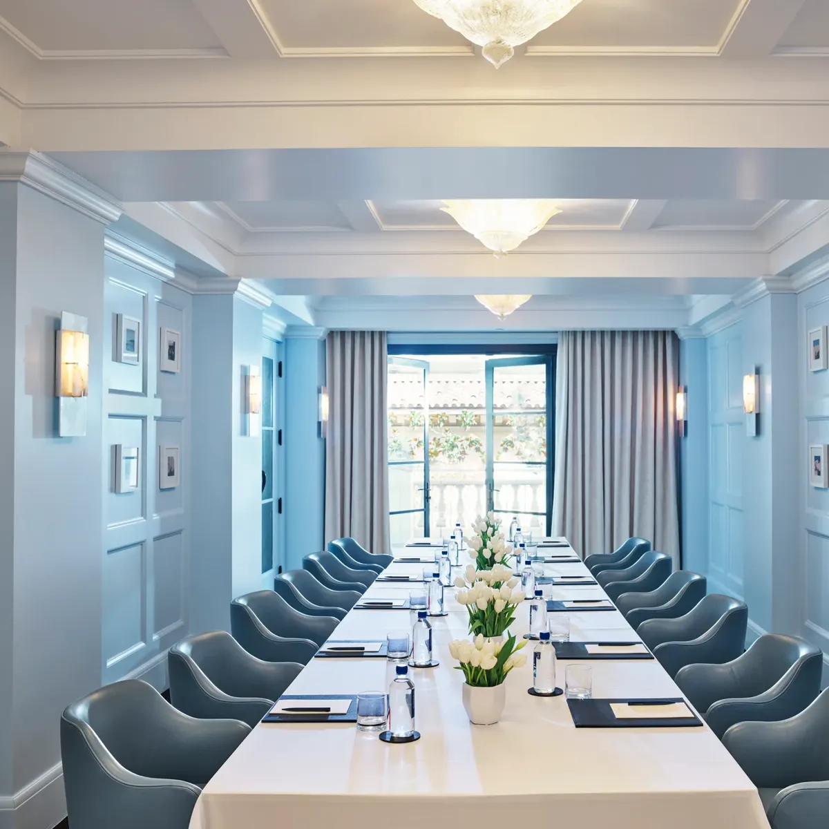 Canon Room boardroom setup with long table, blue paneling, and chandeliers.