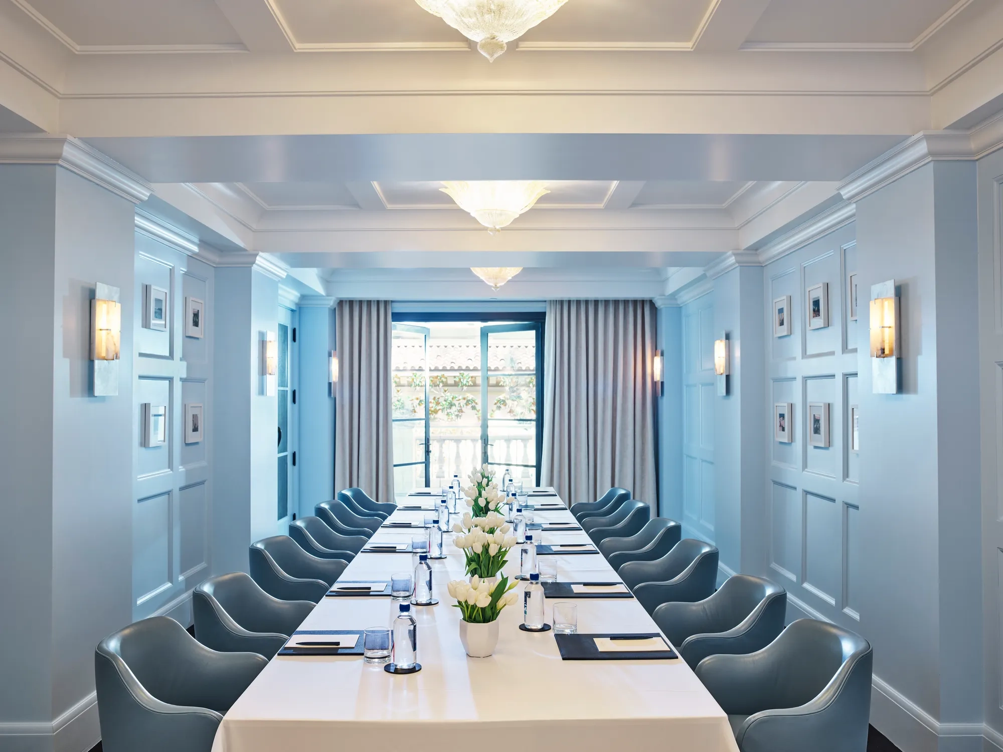 Canon Room boardroom setup with long table, blue paneling, and chandeliers.