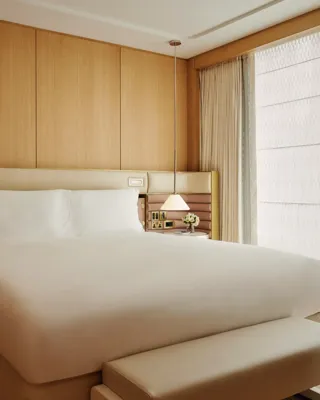 A tidy bedroom with a neatly made bed, soft lighting, and simple furniture.