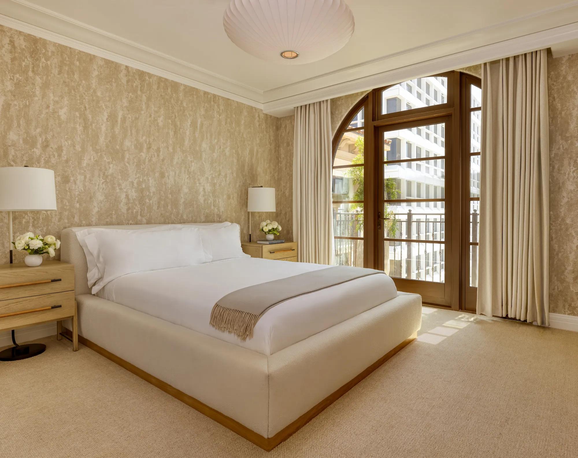 Sophisticated bedroom in the Wilshire Three-Bedroom Residence, with a king-size bed, soft neutral tones, and large windows offering ample natural light.
