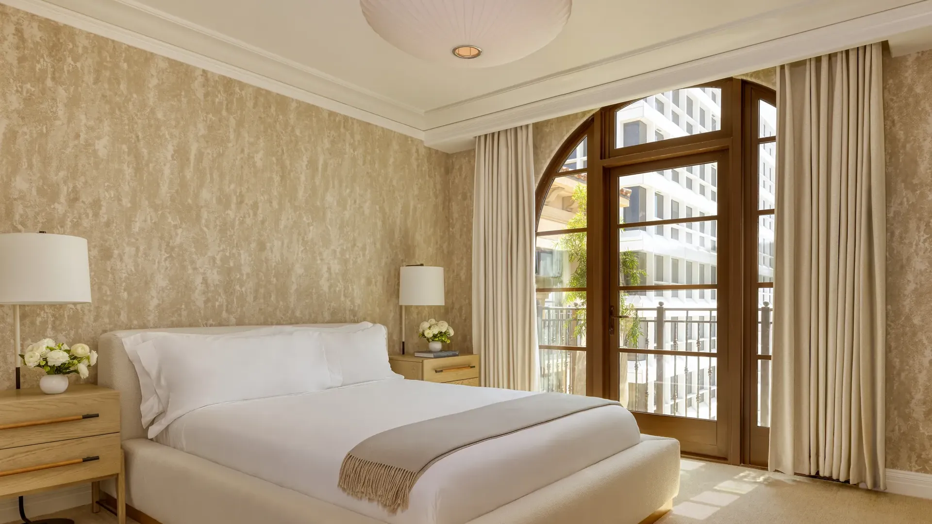 Sophisticated bedroom in the Wilshire Three-Bedroom Residence, with a king-size bed, soft neutral tones, and large windows offering ample natural light.