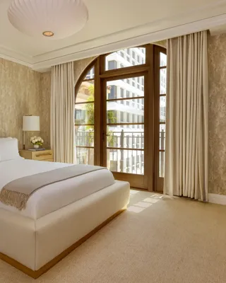 Sophisticated bedroom in the Wilshire Three-Bedroom Residence, with a king-size bed, soft neutral tones, and large windows offering ample natural light.
