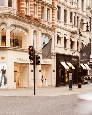 Street view of New Bond Street with luxury storefronts, elegant façades, and pedestrians walking along the upscale shopping district.