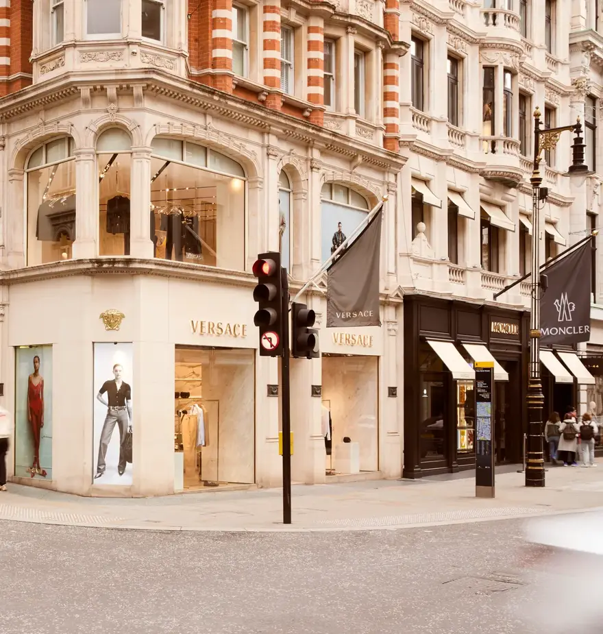 Street view of New Bond Street with luxury storefronts, elegant façades, and pedestrians walking along the upscale shopping district.