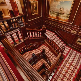 The grand staircase at The Connaught with its elegant curved banister and soft lighting