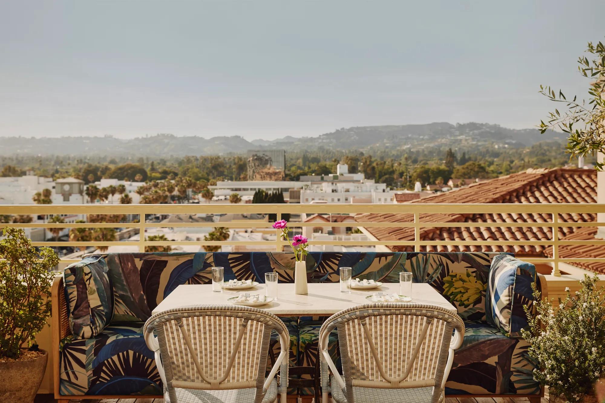 Rooftop terrace table with patterned banquette seating overlooking Beverly Hills rooftops and Hollywood hills.