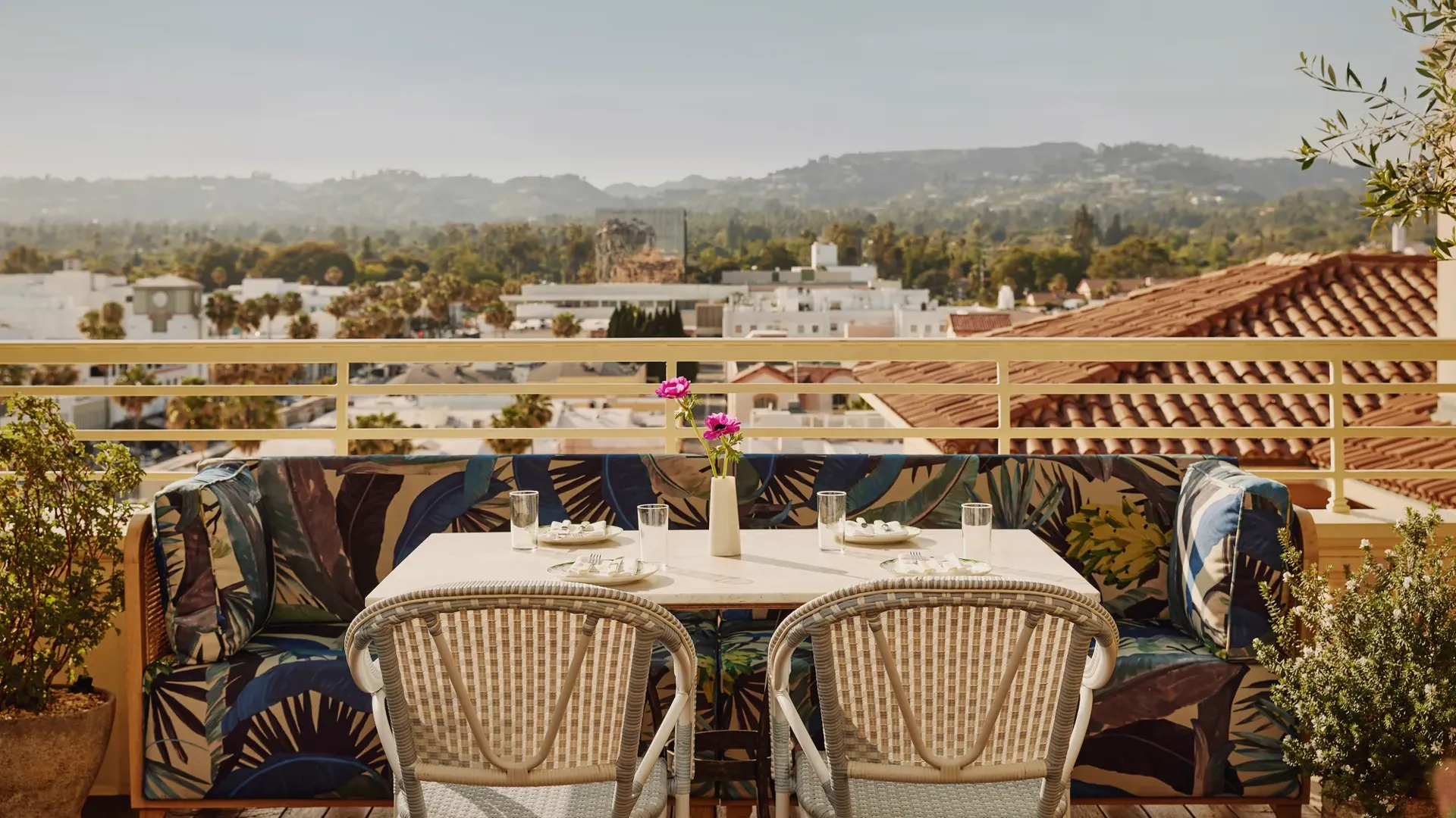 Rooftop terrace table with patterned banquette seating overlooking Beverly Hills rooftops and Hollywood hills.
