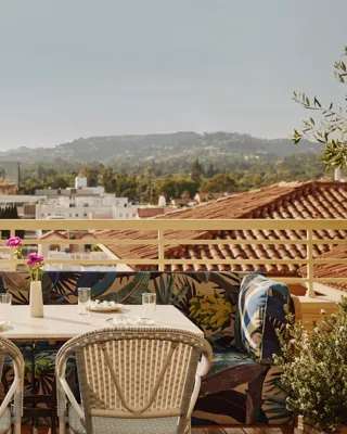 Rooftop terrace table with patterned banquette seating overlooking Beverly Hills rooftops and Hollywood hills.