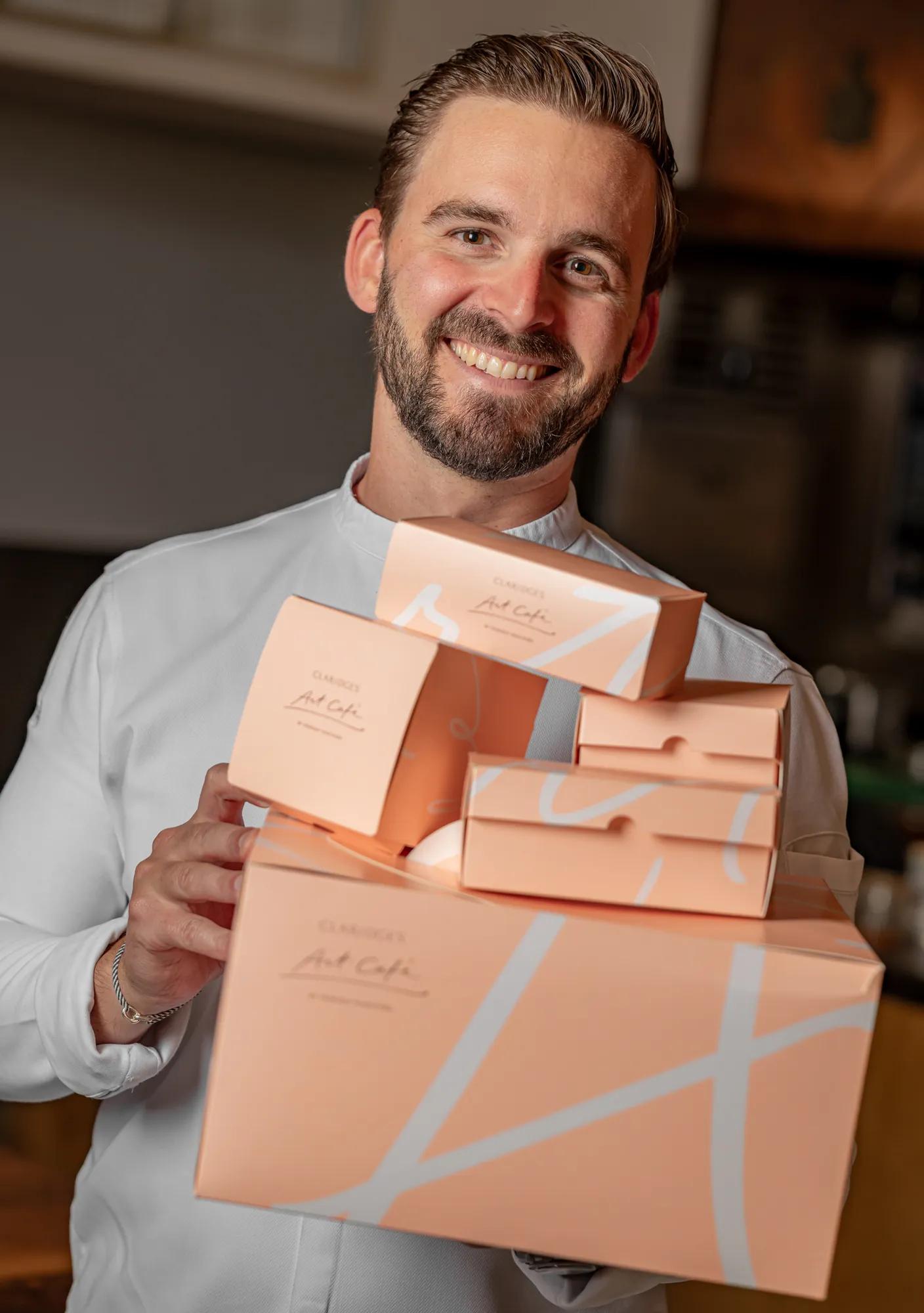 Chef holding a selection of Claridge’s Art Café pâtisserie gift boxes.
