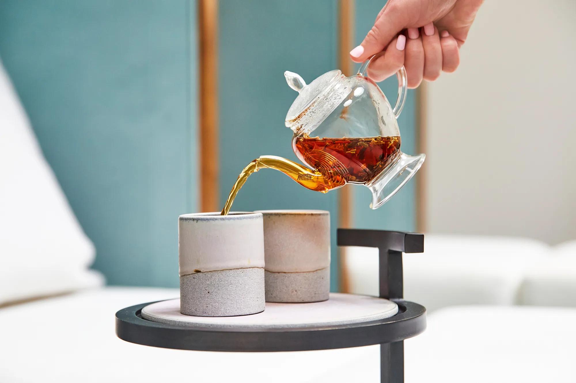 Tea being poured into ceramic cups on side table in spa relaxation area