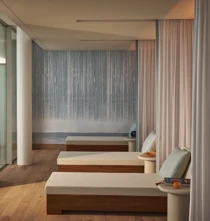 Relaxation area in Surrenne featuring white lounge chairs with soft cushions, separated by light curtains, and a calming wall with a gradient blue design, evoking a peaceful and serene atmosphere.