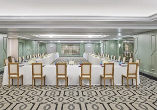 The Gallery set in U-shape for a meeting: white-linen tables, wood chairs, hydrangea centerpieces, and pads with pens.