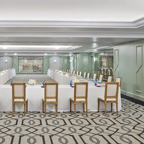 The Gallery set in U-shape for a meeting: white-linen tables, wood chairs, hydrangea centerpieces, and pads with pens.