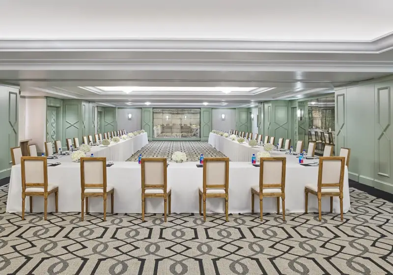 The Gallery set in U-shape for a meeting: white-linen tables, wood chairs, hydrangea centerpieces, and pads with pens.