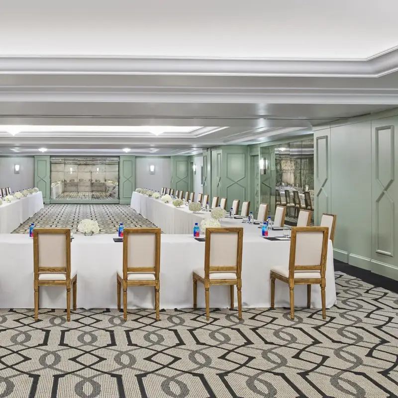 The Gallery set in U-shape for a meeting: white-linen tables, wood chairs, hydrangea centerpieces, and pads with pens.