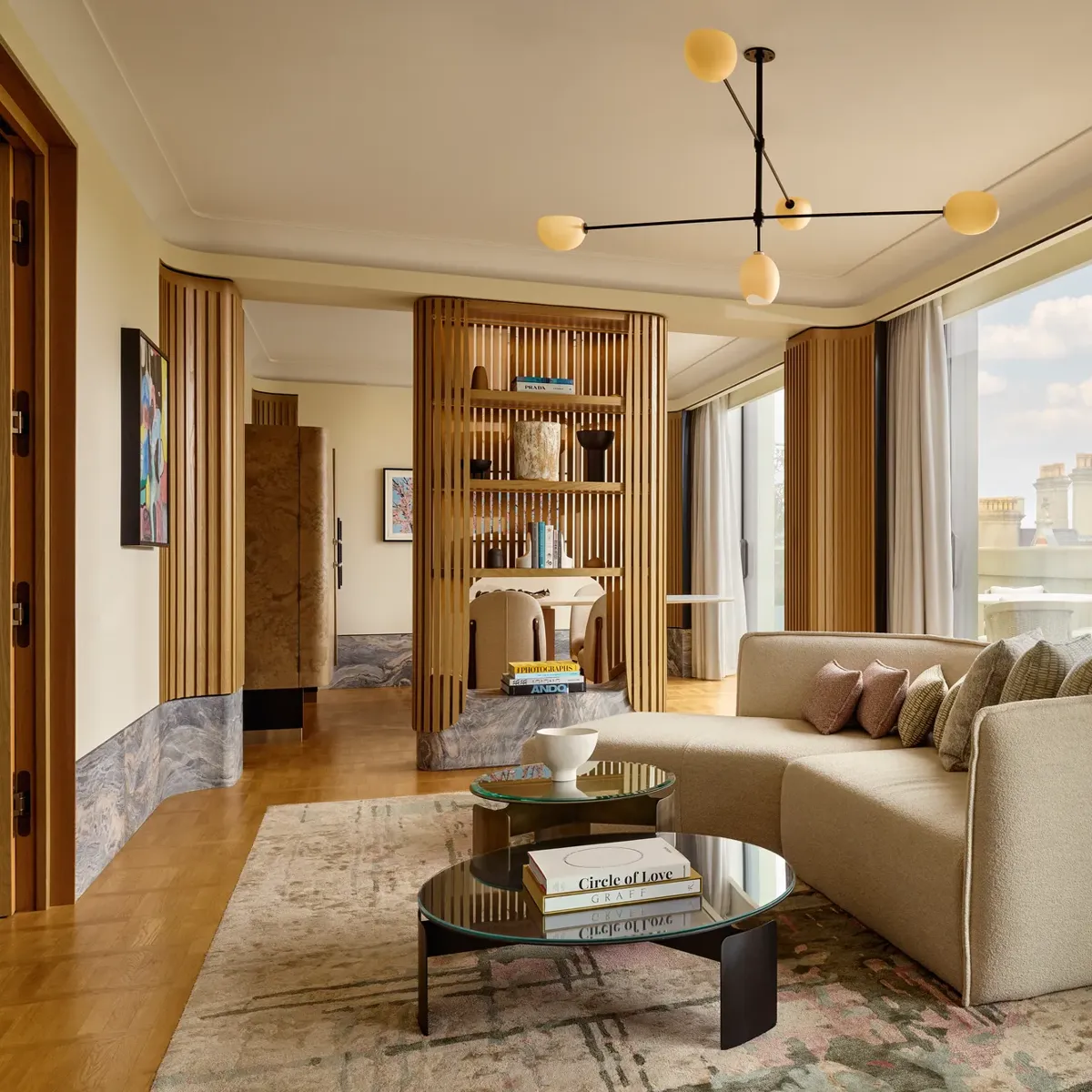 Stylish suite with curved sofa, modern lighting, city views, and natural wood panelling creating a serene, luxurious space