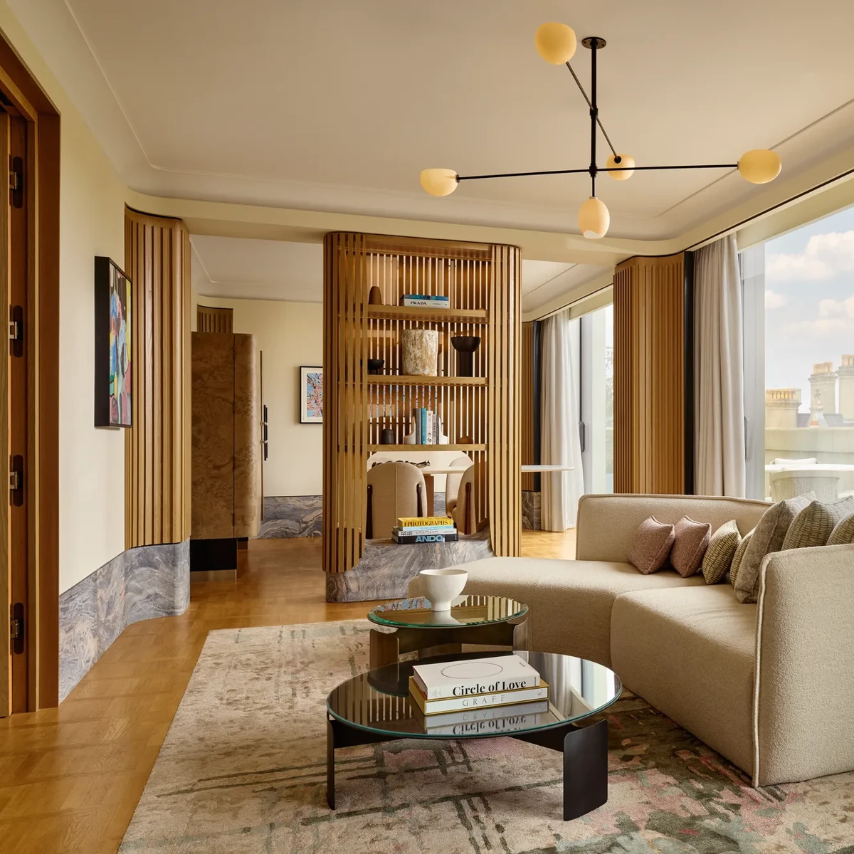 Stylish suite with curved sofa, modern lighting, city views, and natural wood panelling creating a serene, luxurious space