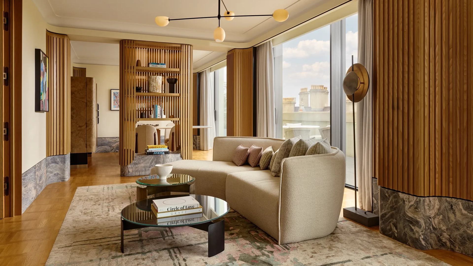 Stylish suite with curved sofa, modern lighting, city views, and natural wood panelling creating a serene, luxurious space