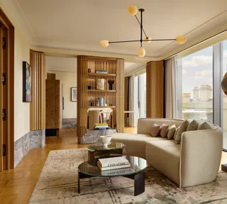 Stylish suite with curved sofa, modern lighting, city views, and natural wood panelling creating a serene, luxurious space