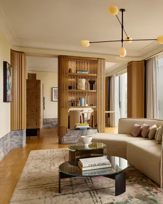 Stylish suite with curved sofa, modern lighting, city views, and natural wood panelling creating a serene, luxurious space