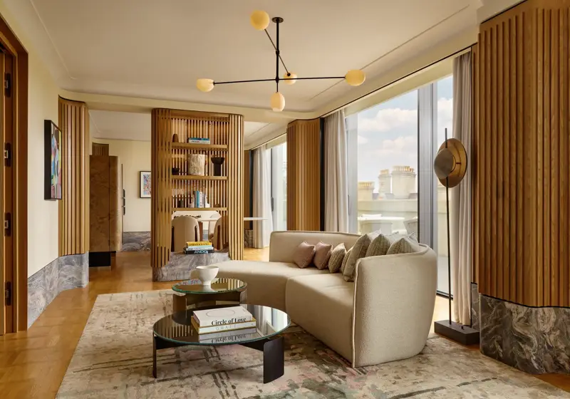 Stylish suite with curved sofa, modern lighting, city views, and natural wood panelling creating a serene, luxurious space