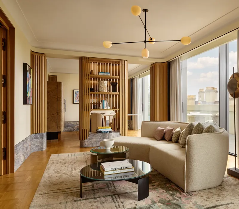 Stylish suite with curved sofa, modern lighting, city views, and natural wood panelling creating a serene, luxurious space