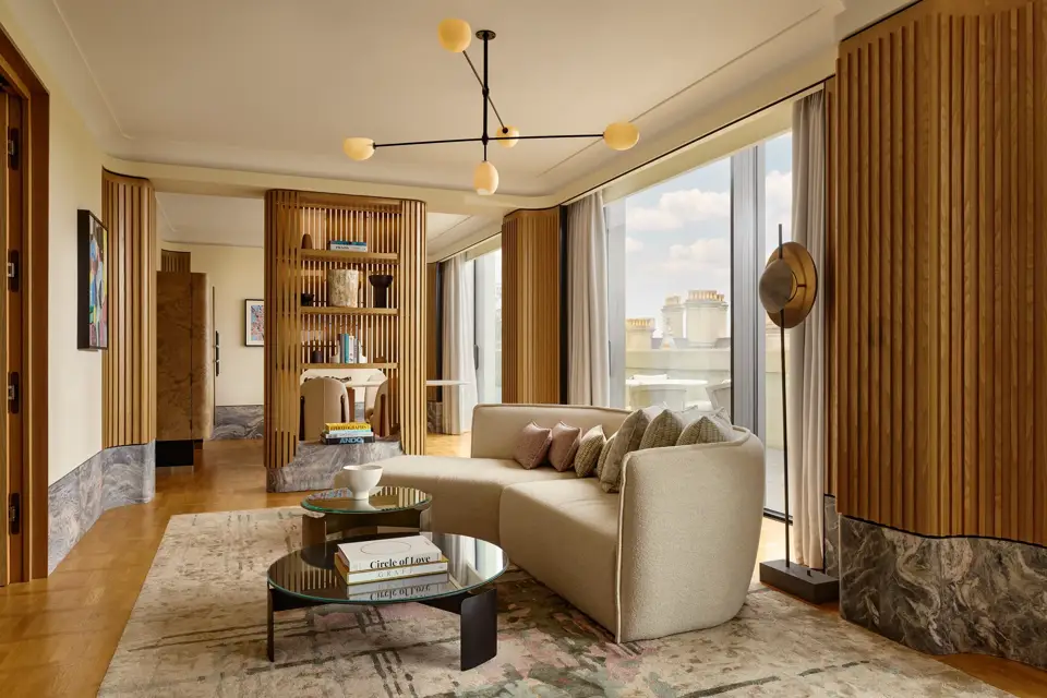 Stylish suite with curved sofa, modern lighting, city views, and natural wood panelling creating a serene, luxurious space