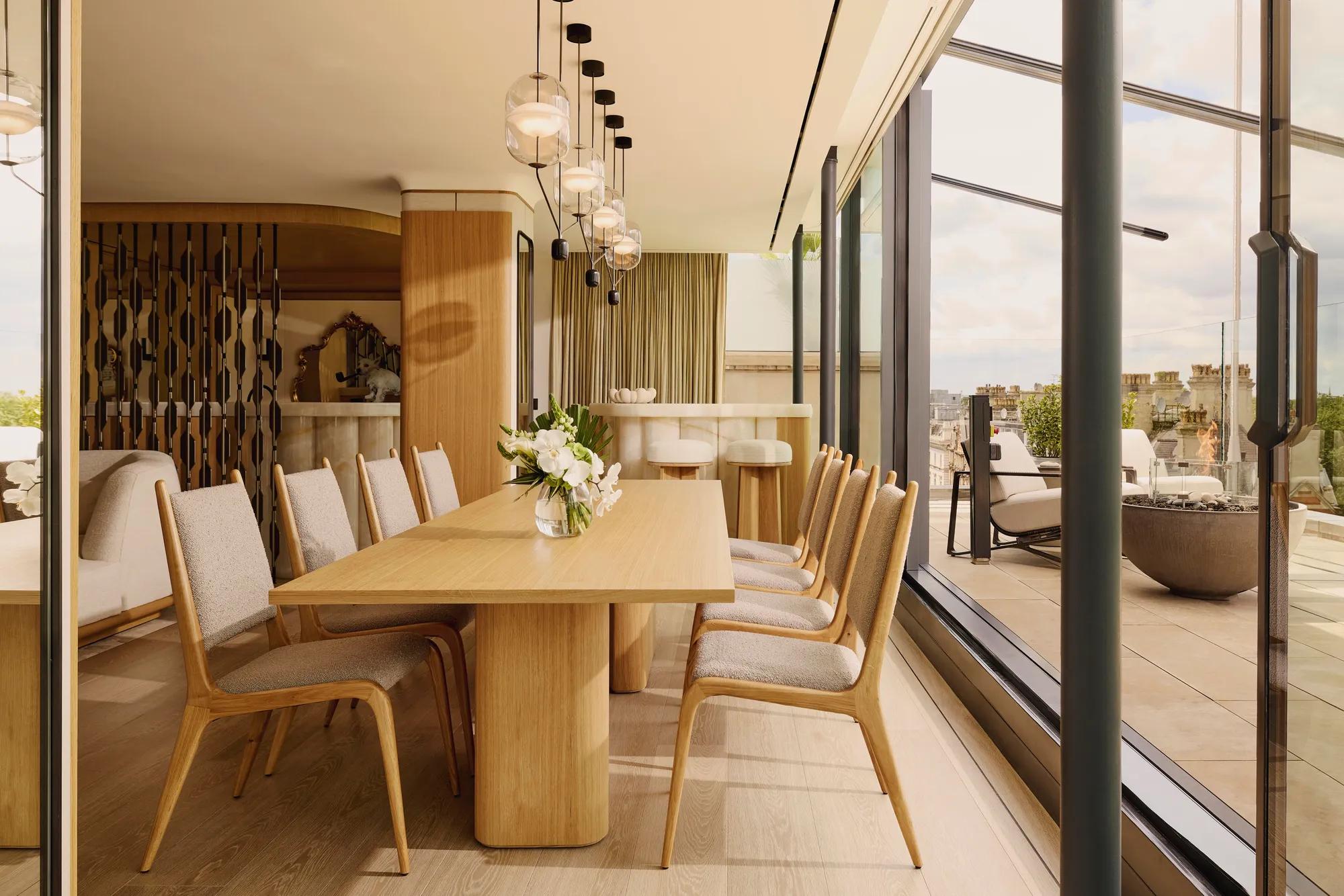 ChatGPT said:

A bright dining area with a wooden table and chairs, pendant lighting, and glass doors opening to a terrace with city views