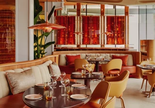 Vibrant dining room with curved banquettes, warm-toned chairs, and contemporary red and orange décor.