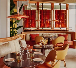 Vibrant dining room with curved banquettes, warm-toned chairs, and contemporary red and orange décor.