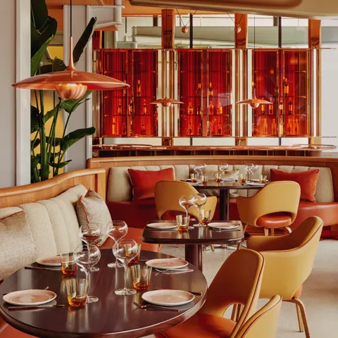 Vibrant dining room with curved banquettes, warm-toned chairs, and contemporary red and orange décor.
