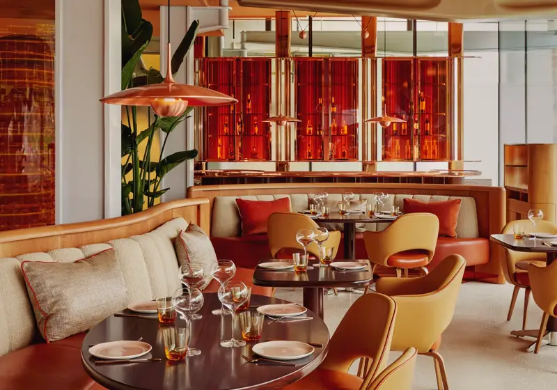 Vibrant dining room with curved banquettes, warm-toned chairs, and contemporary red and orange décor.
