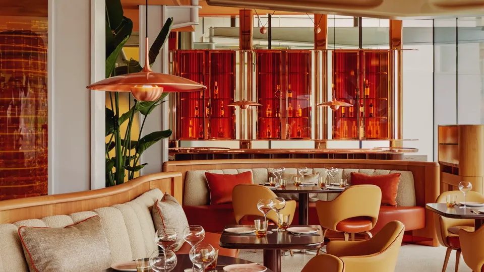 Vibrant dining room with curved banquettes, warm-toned chairs, and contemporary red and orange décor.